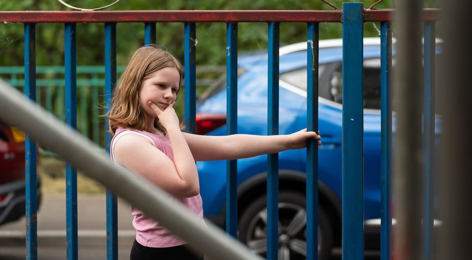 Young girl holding a metal fence
