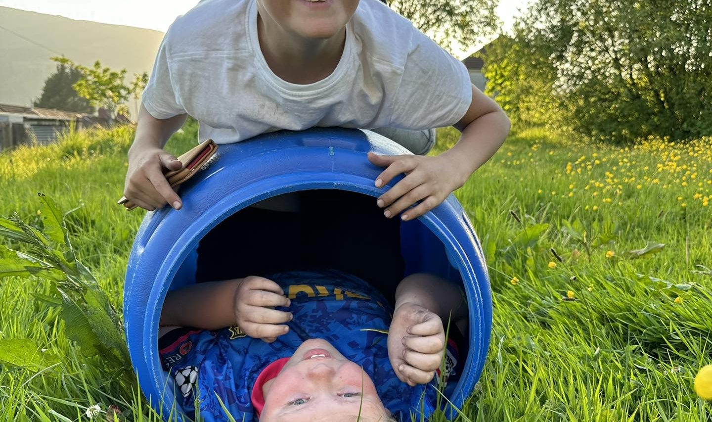 Young boy in a blue tube, with another boy on top of the tube