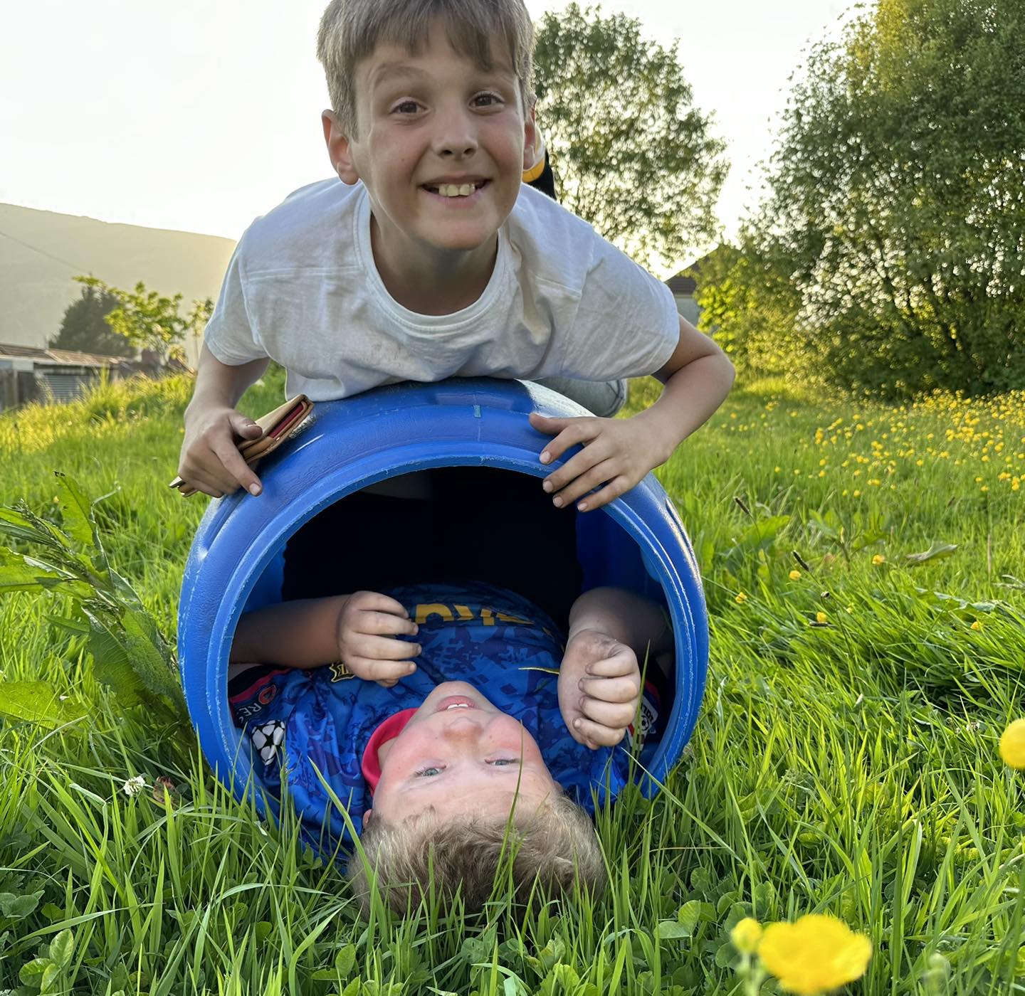 Young boy in a blue tube, with another boy on top of the tube
